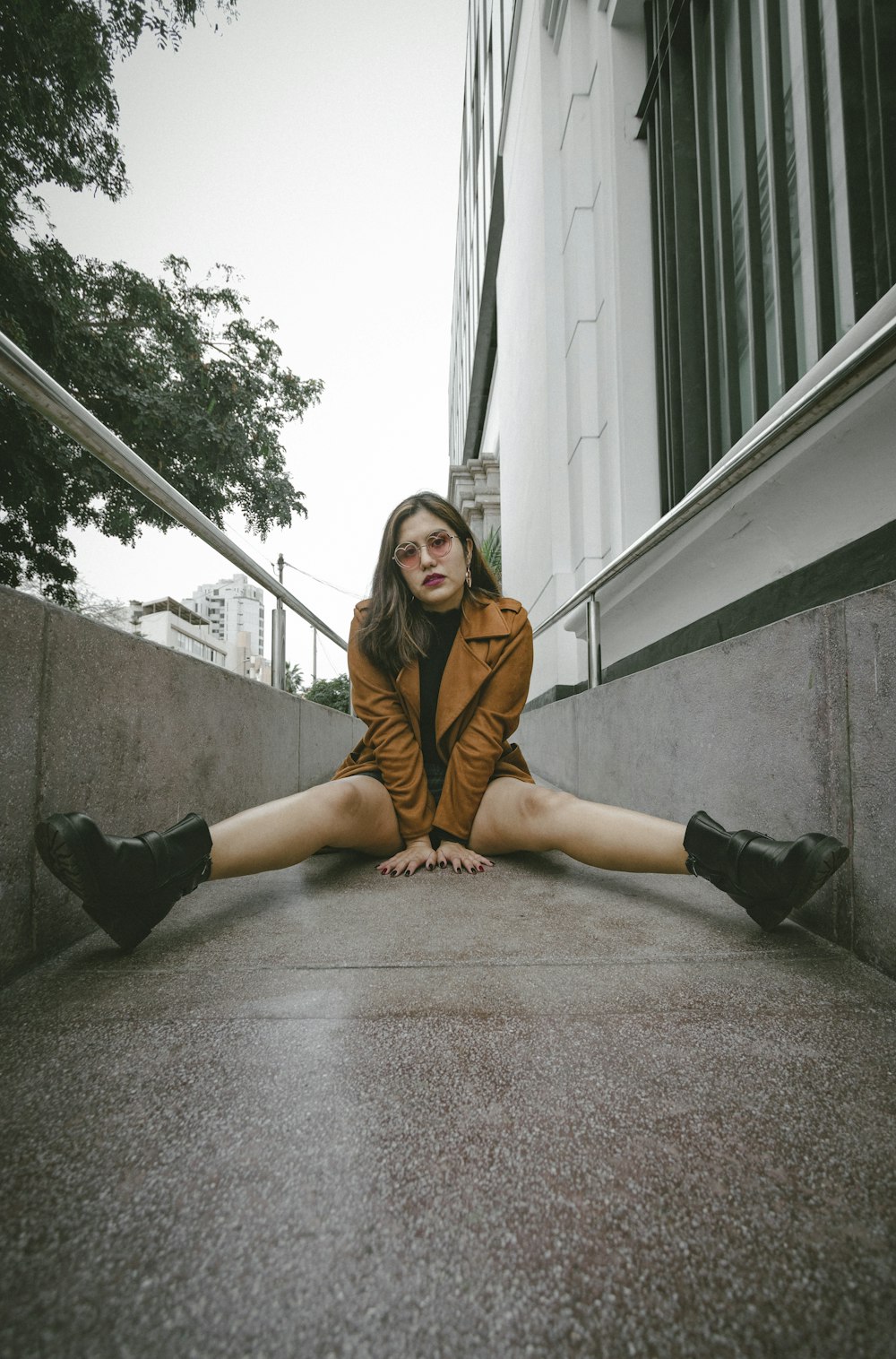 woman in brown coat sitting on gray concrete stairs