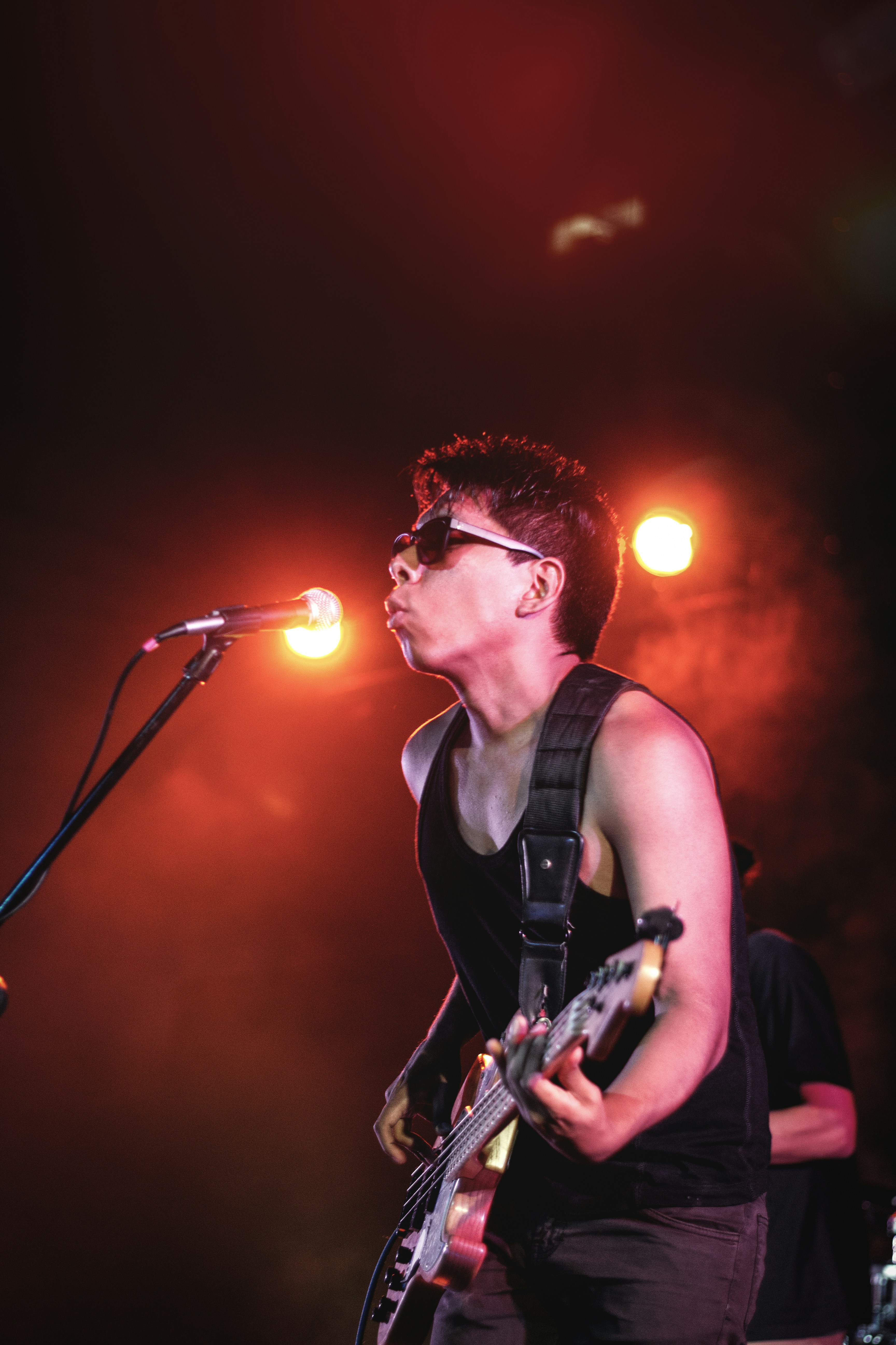 man in black tank top playing guitar