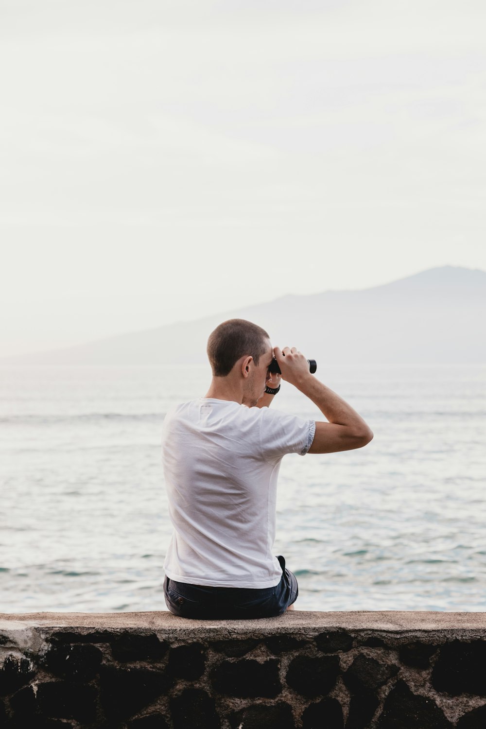 man in white t-shirt and black shorts standing on rock formation during daytime