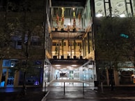 Exterior night view of Farmavale Pimenteira illuminated with brand colors.