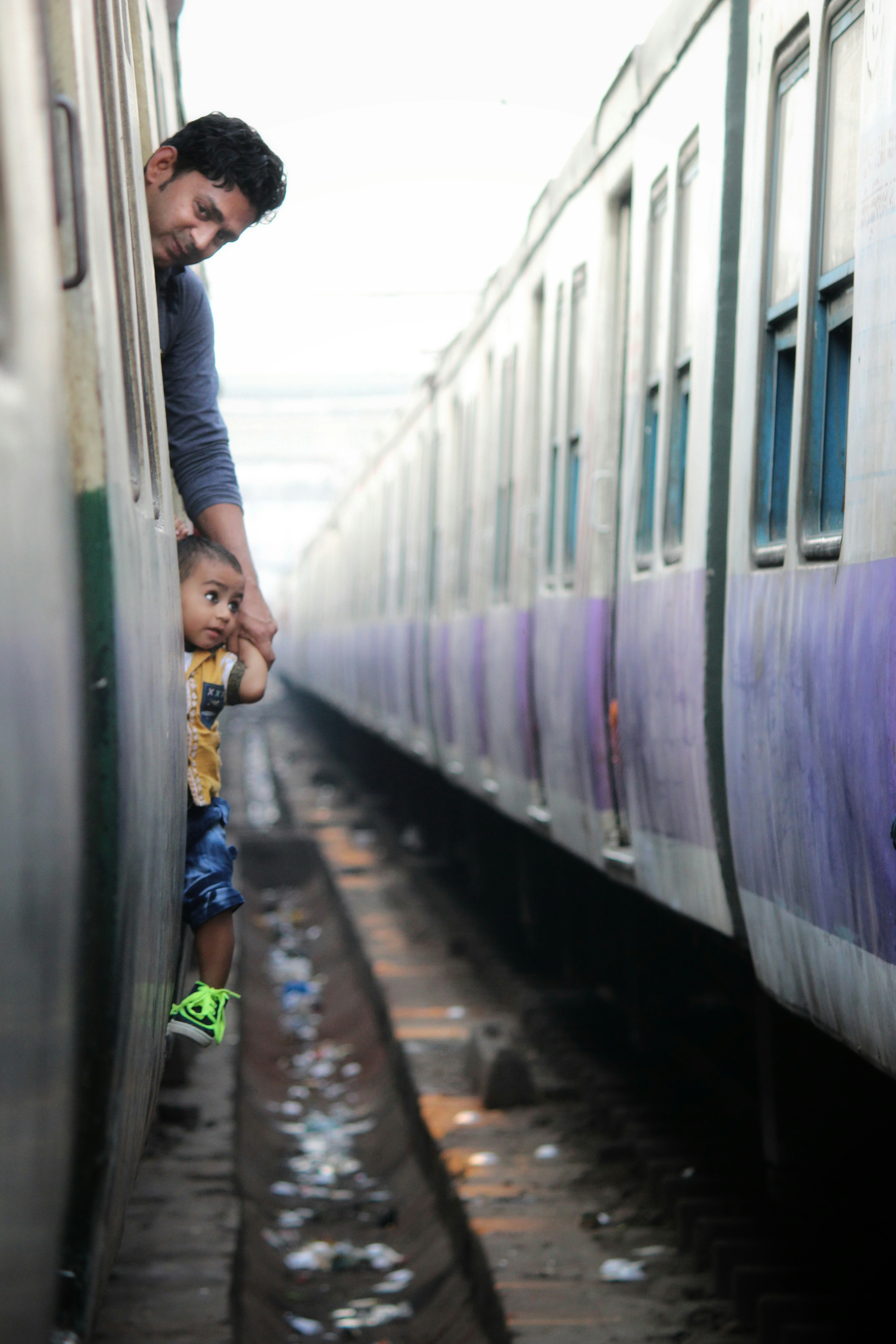 homme en veste noire debout à côté d’un train blanc et violet