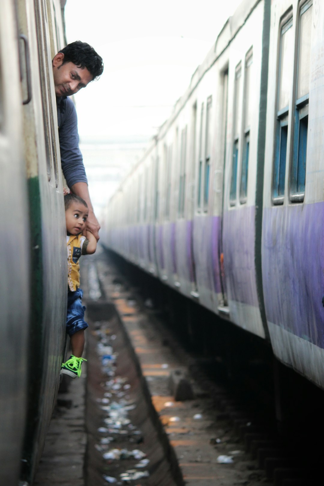 man in black jacket standing beside white and purple train
