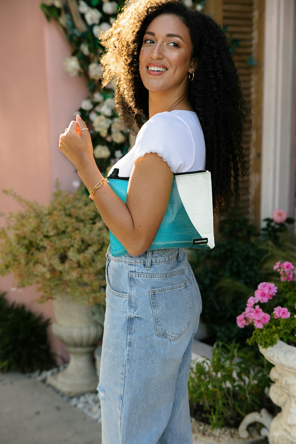 woman in white shirt and blue denim jeans holding white book