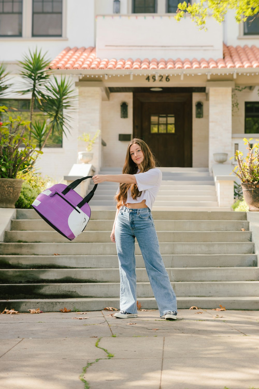 woman in white long sleeve shirt and blue denim jeans holding pink and black handbag