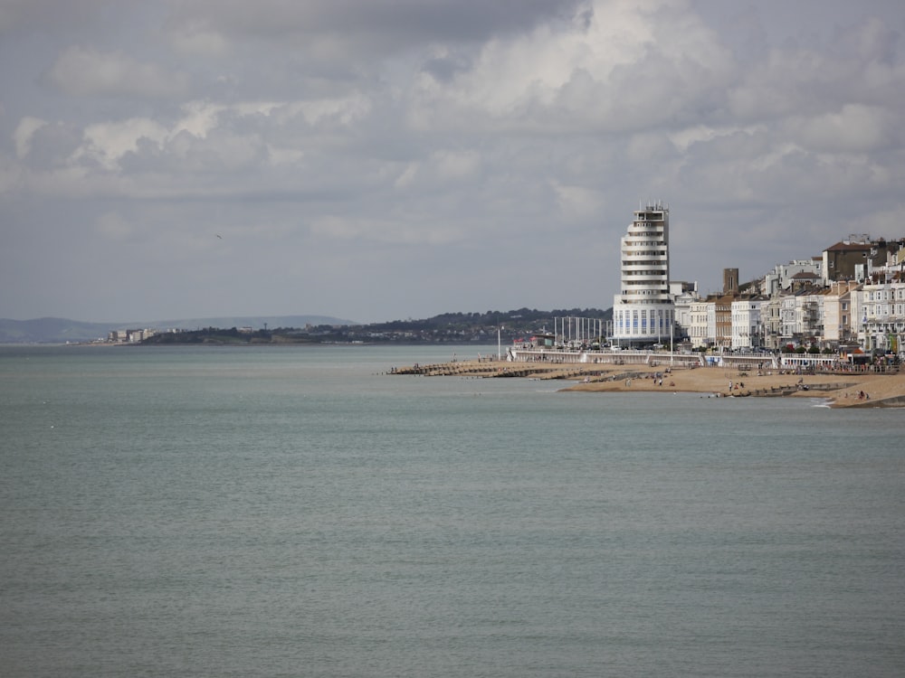 white concrete building near sea under white clouds during daytime