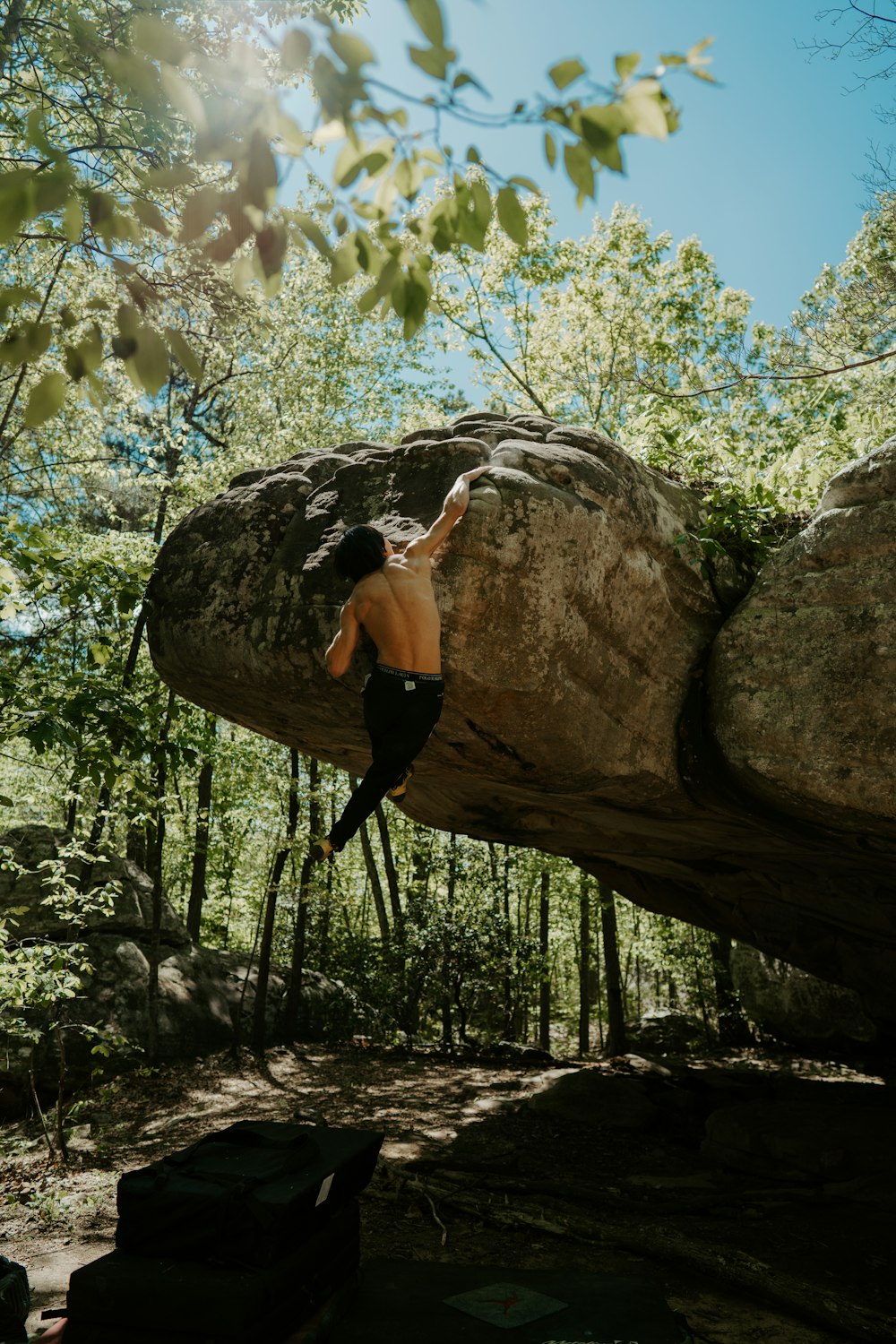 Frau in schwarzem Tanktop und schwarzer Leggings klettert tagsüber auf braunen Fels