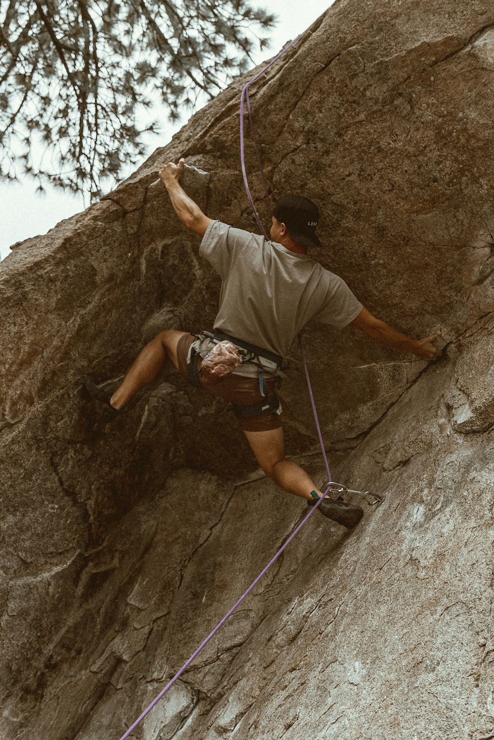 man in white t-shirt climbing on rocky mountain during daytime