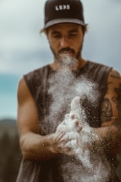 man in black tank top blowing white powder