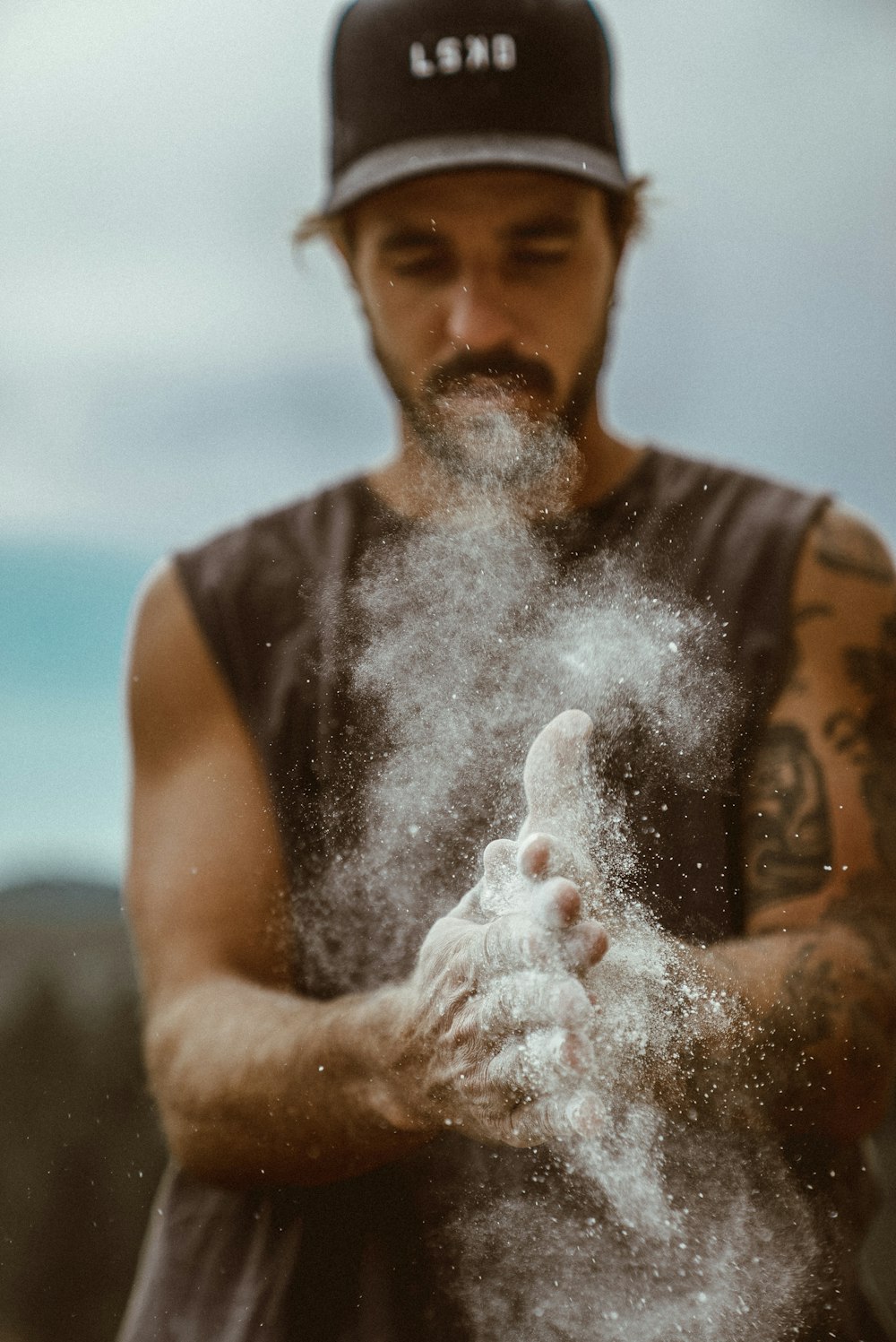 man in black tank top blowing white powder