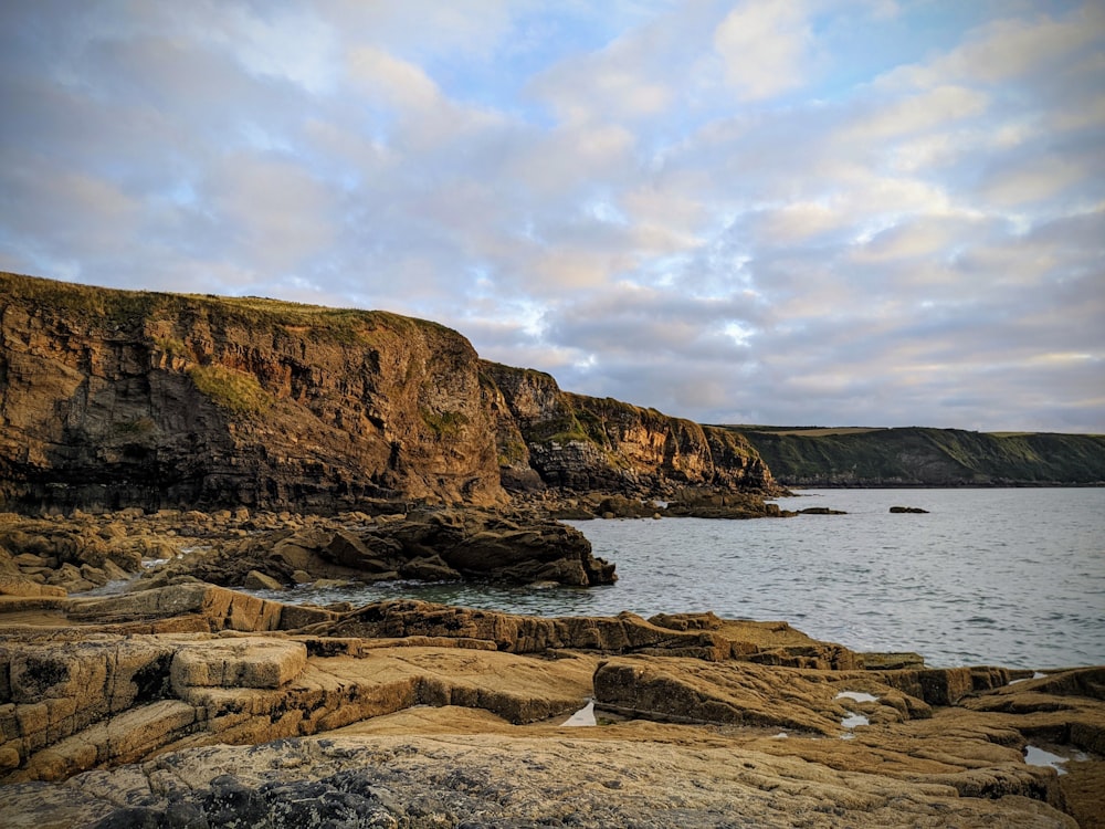 brown rock formation near body of water during daytime