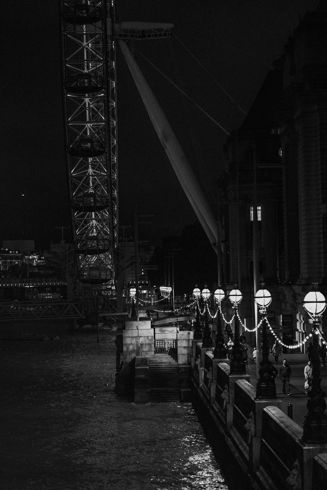 grayscale photo of people standing near metal tower