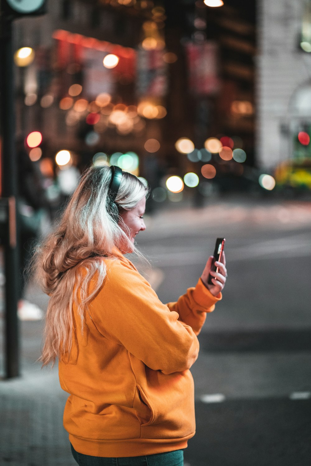 woman in orange jacket holding smartphone