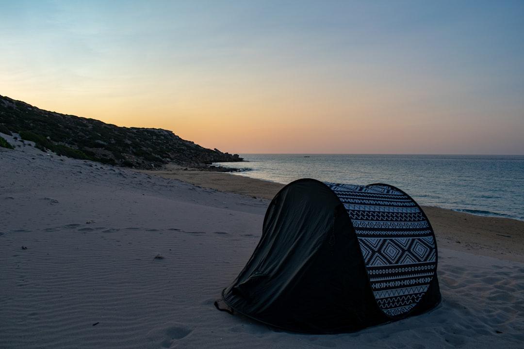 black and white tent on beach during sunset