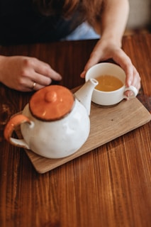 person pouring white liquid on white ceramic teapot