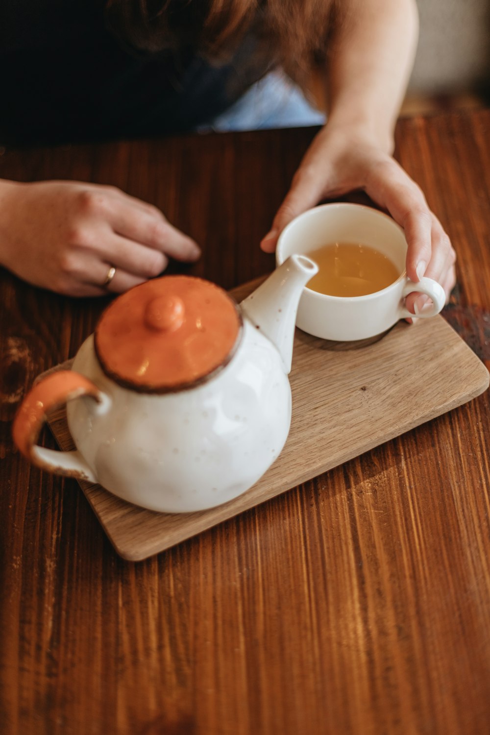 person pouring white liquid on white ceramic teapot