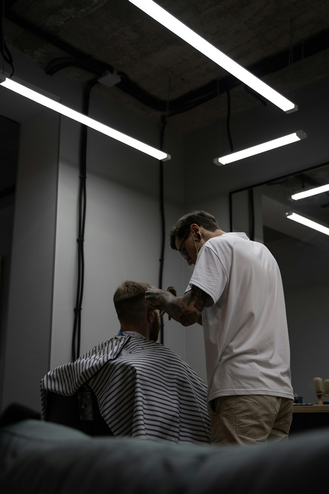 man in white shirt cutting hair of man in black and white stripe shirt