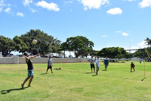 people playing soccer on green grass field during daytime