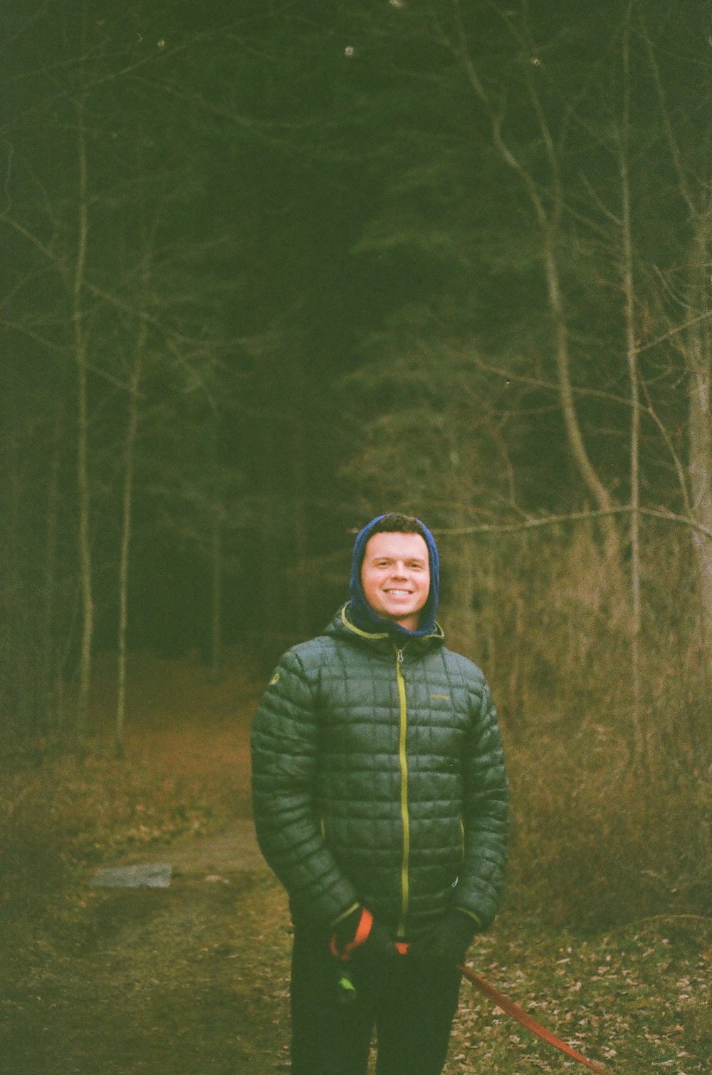 a man in a green jacket standing in the woods