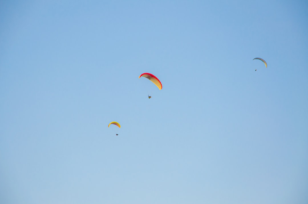 people riding on red and yellow parachute