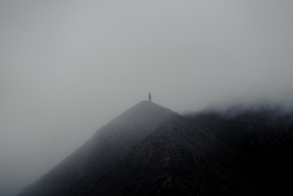 Silhouette der Person, die an einem nebligen Tag auf dem Gipfel des Berges steht