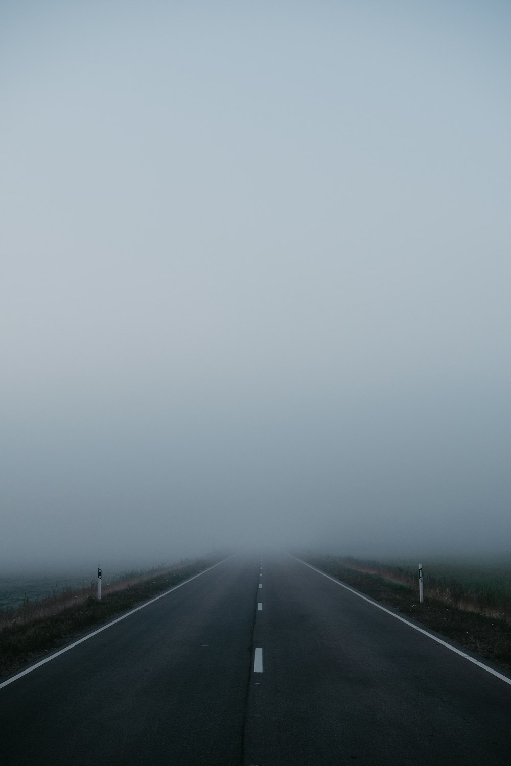 灰色の空の下の黒いアスファルト道路