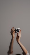 Close-up of hands holding a vintage camera against a charcoal gray background