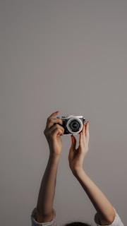 Close-up of hands holding a vintage camera against a charcoal gray background