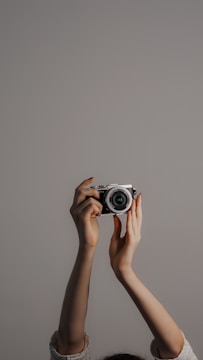 Close-up of hands holding a vintage camera against a charcoal gray background