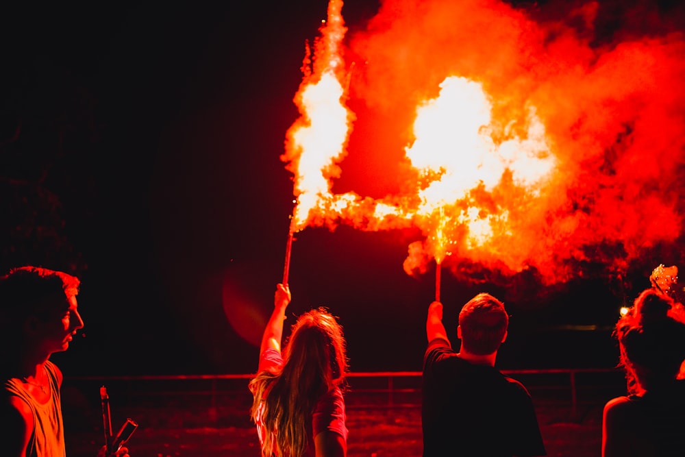 people standing and sitting on the street with orange fire