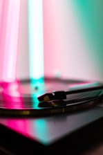 Close-up of a retro boombox playing vinyl records with vibrant neon lights in the background.