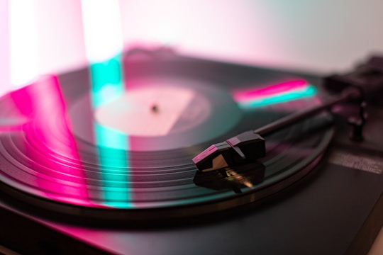 Close-up of a vinyl record spinning under soft colorful lights.