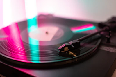 Close-up of a glowing purple vinyl record spinning on a vintage turntable with dark metallic textures in the background