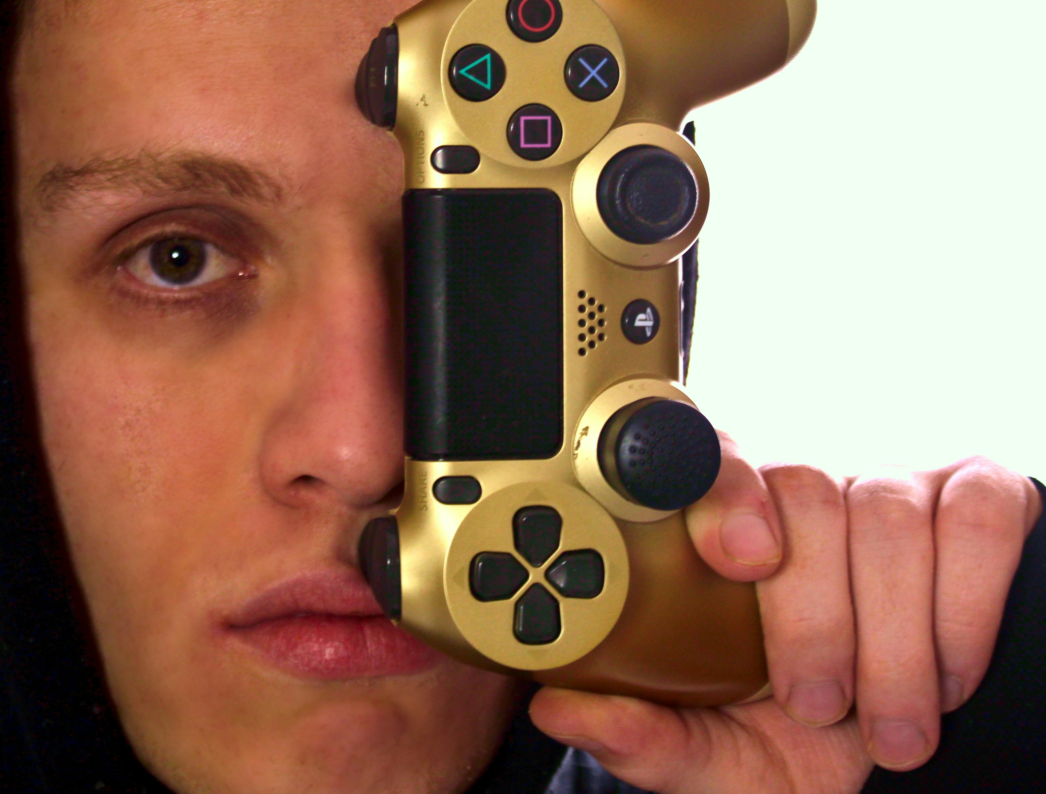 Hombre sosteniendo el controlador de juego de Sony PS 4 dorado y negro