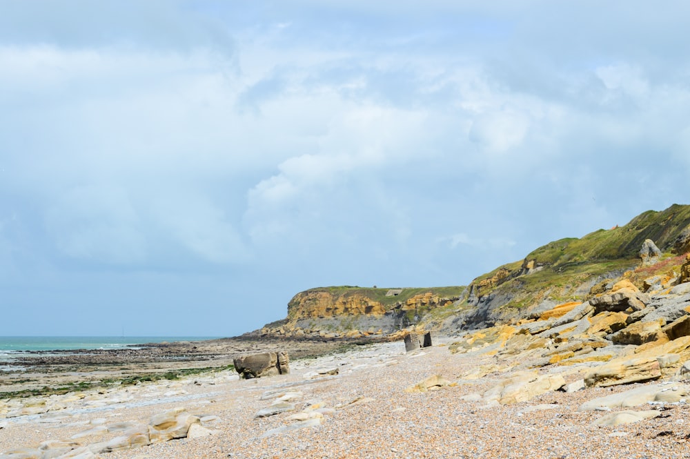 brown rock formation on beach under white clouds during daytime