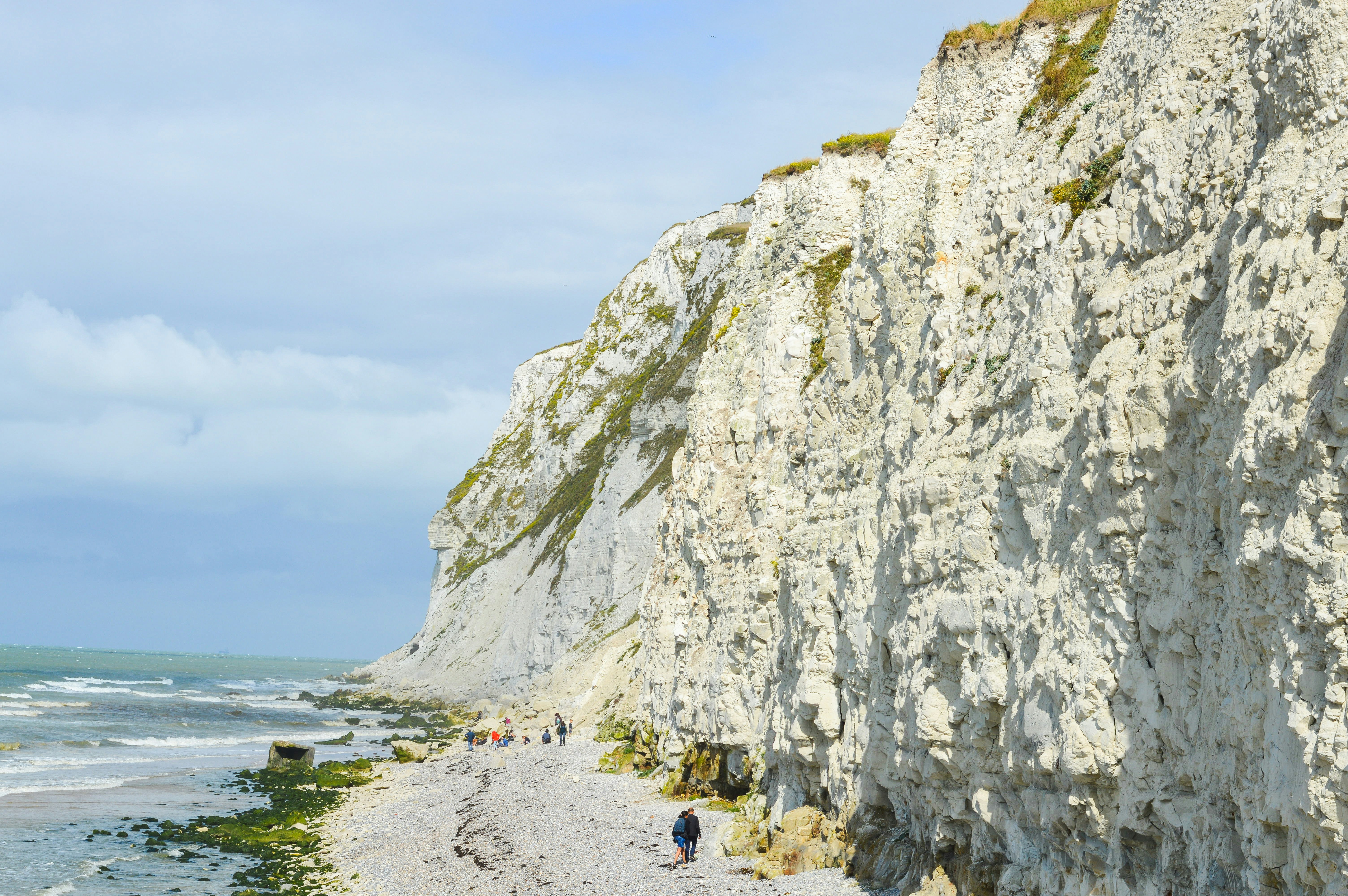 people on beach near rocky mountain during daytime