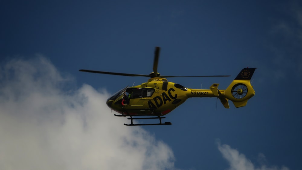 yellow and black helicopter flying in the sky during daytime
