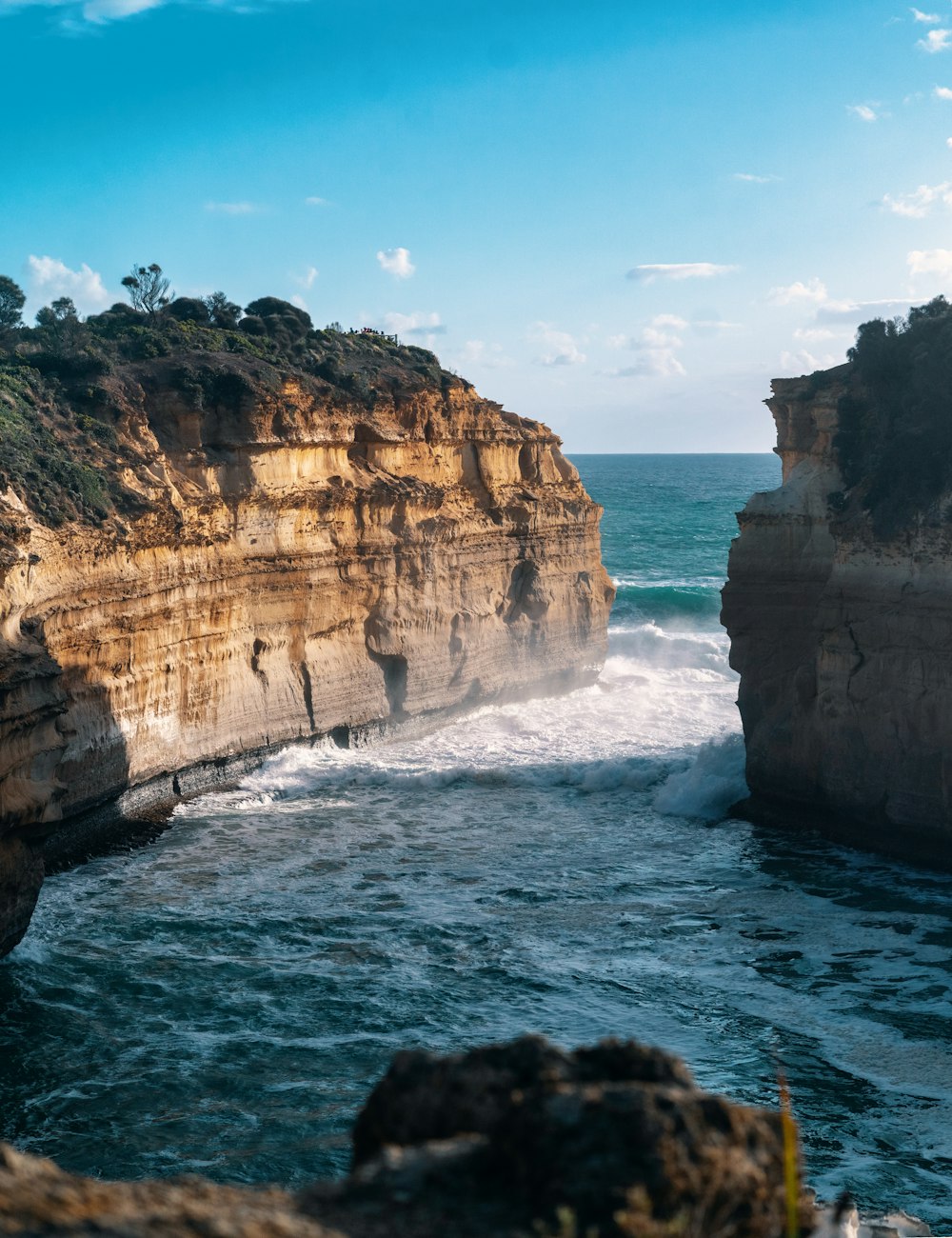 brown rock formation on sea under blue sky during daytime