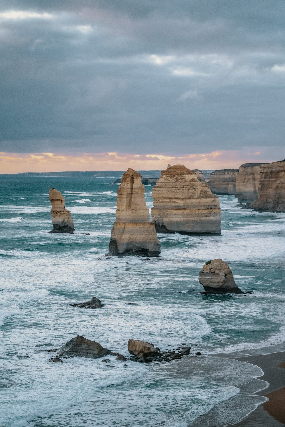 brown rock formation on sea under cloudy sky during daytime