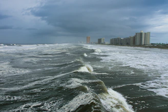 ocean waves near city buildings during daytime