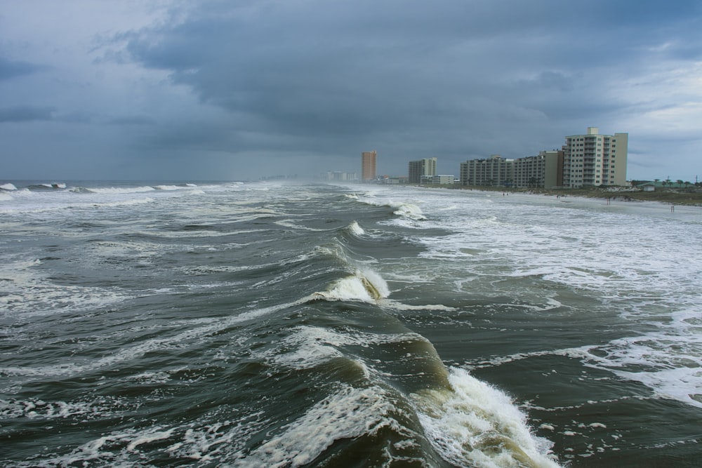 ocean waves near city buildings during daytime