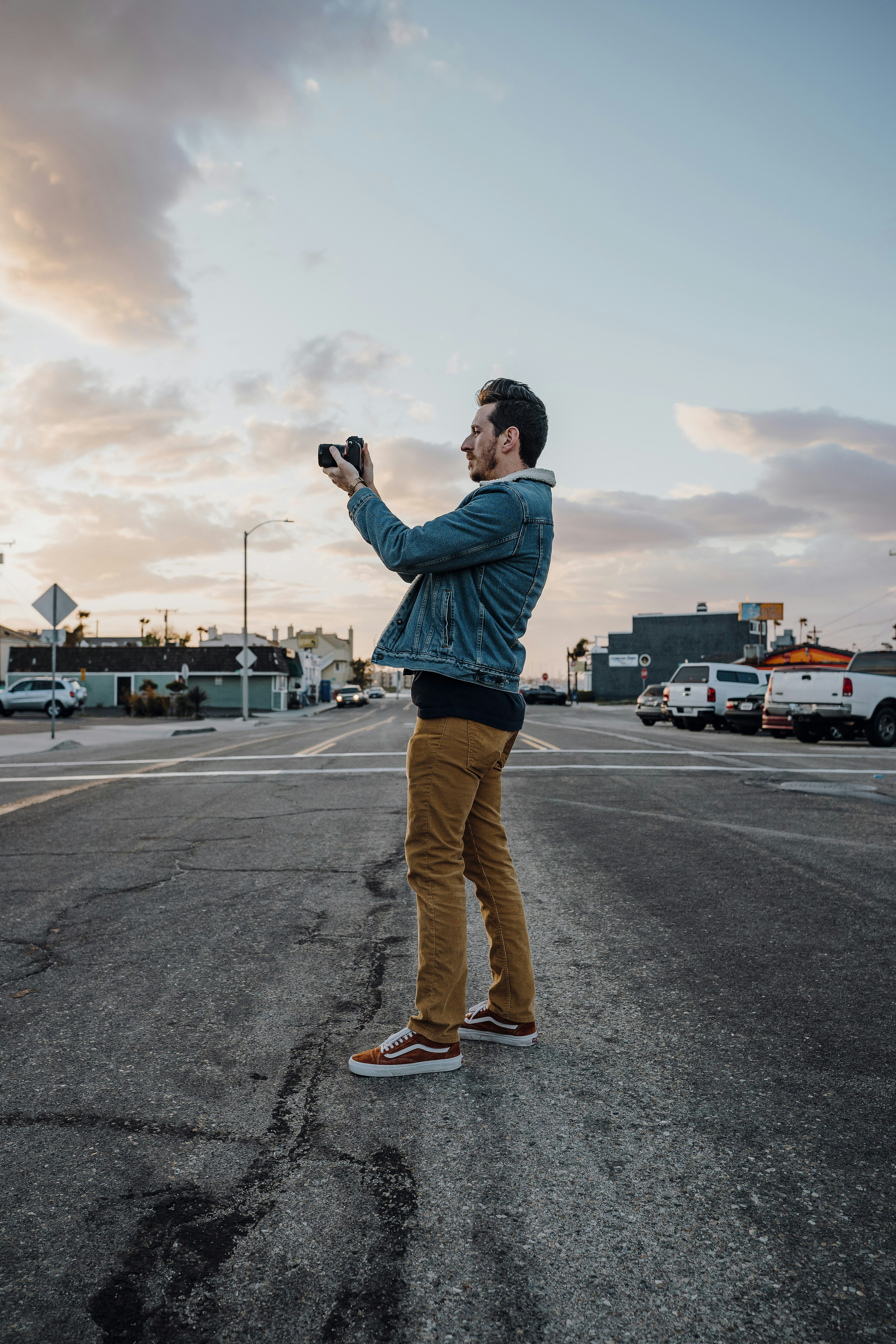 Man in blue jacket and brown pants standing on road during daytime