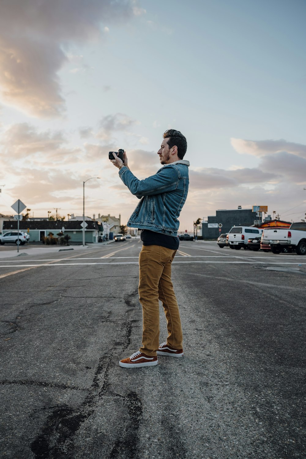 man in blue jacket and brown pants standing on road during daytime