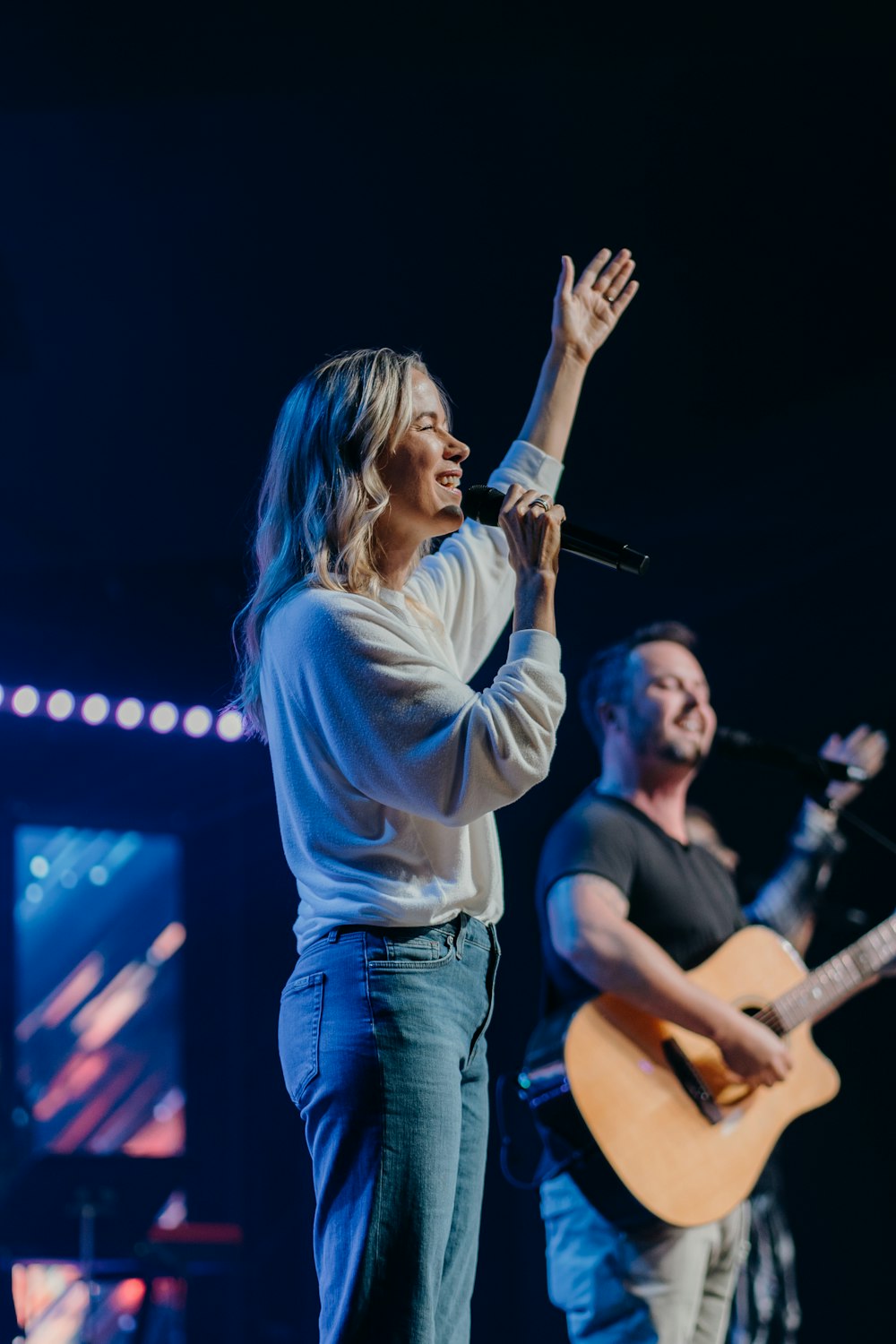 woman in white long sleeve shirt singing on stage