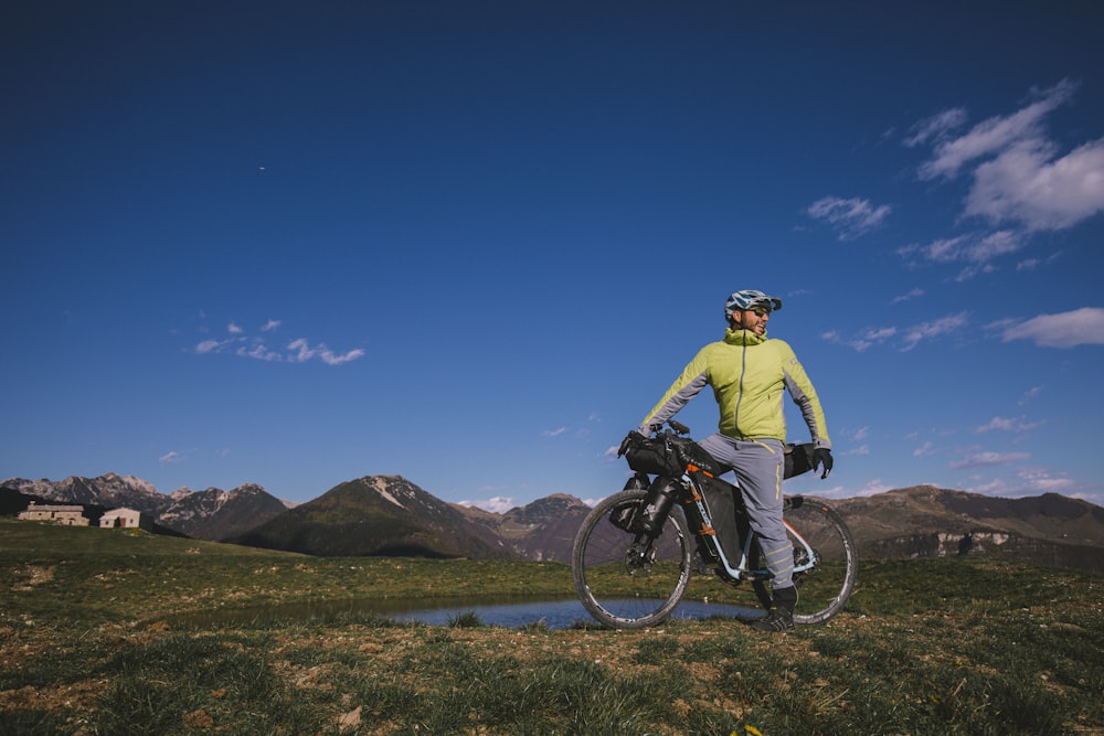 man in yellow jacket riding bicycle on dirt road during daytime