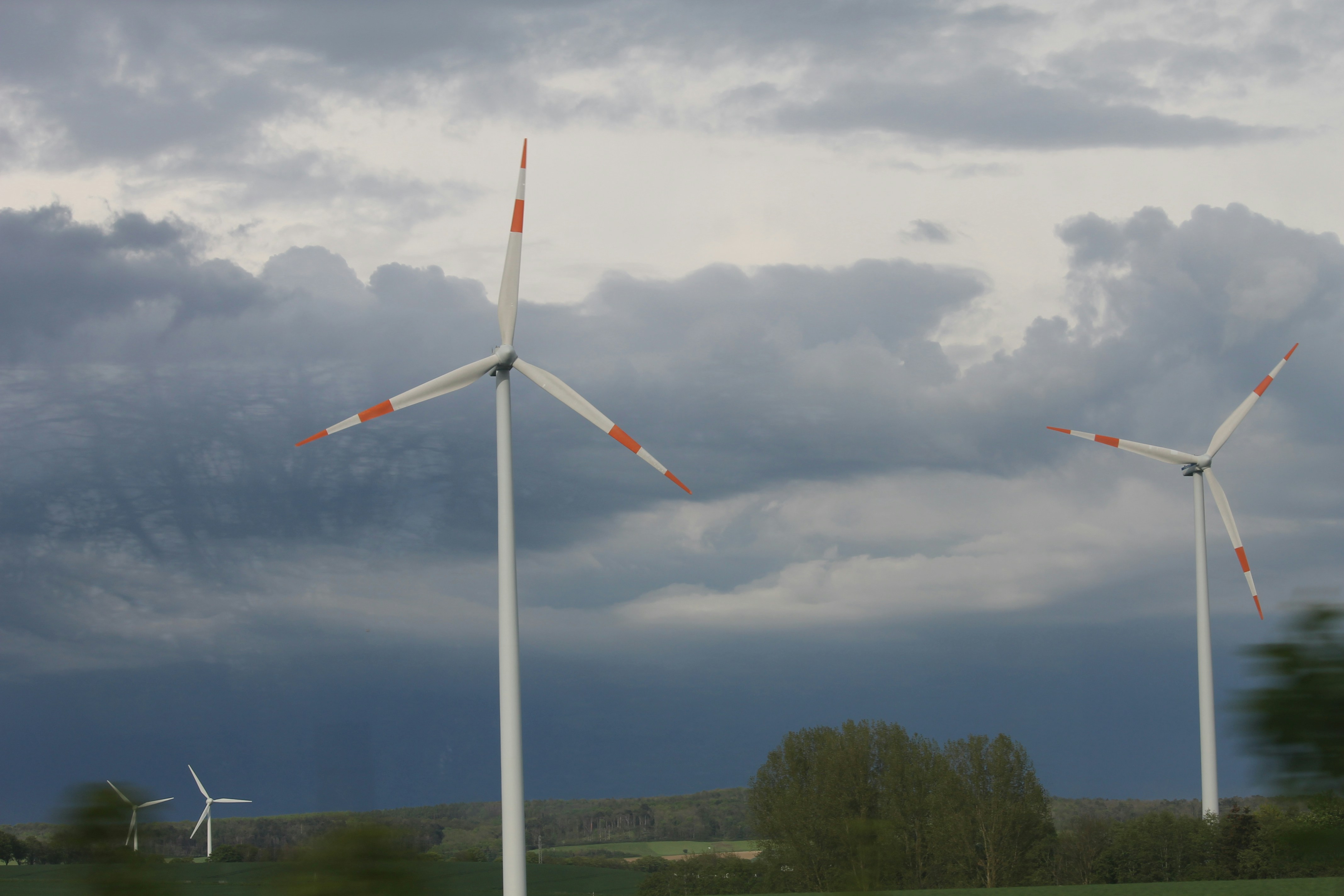 A red and white wind turbine under a blue sky