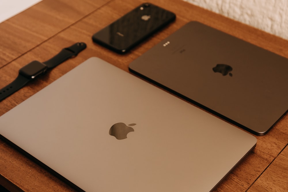 silver macbook beside black iphone 7 on brown wooden table