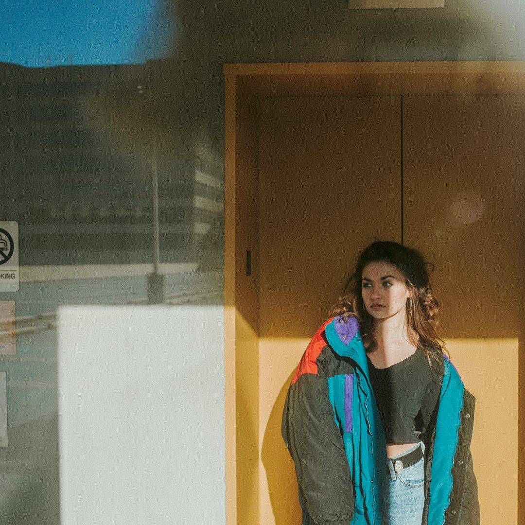 woman in blue jacket standing near brown wooden door