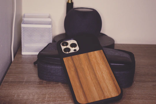A rustic wooden phone stand displayed on a desk, crafted from reclaimed wood with visible grain patterns.