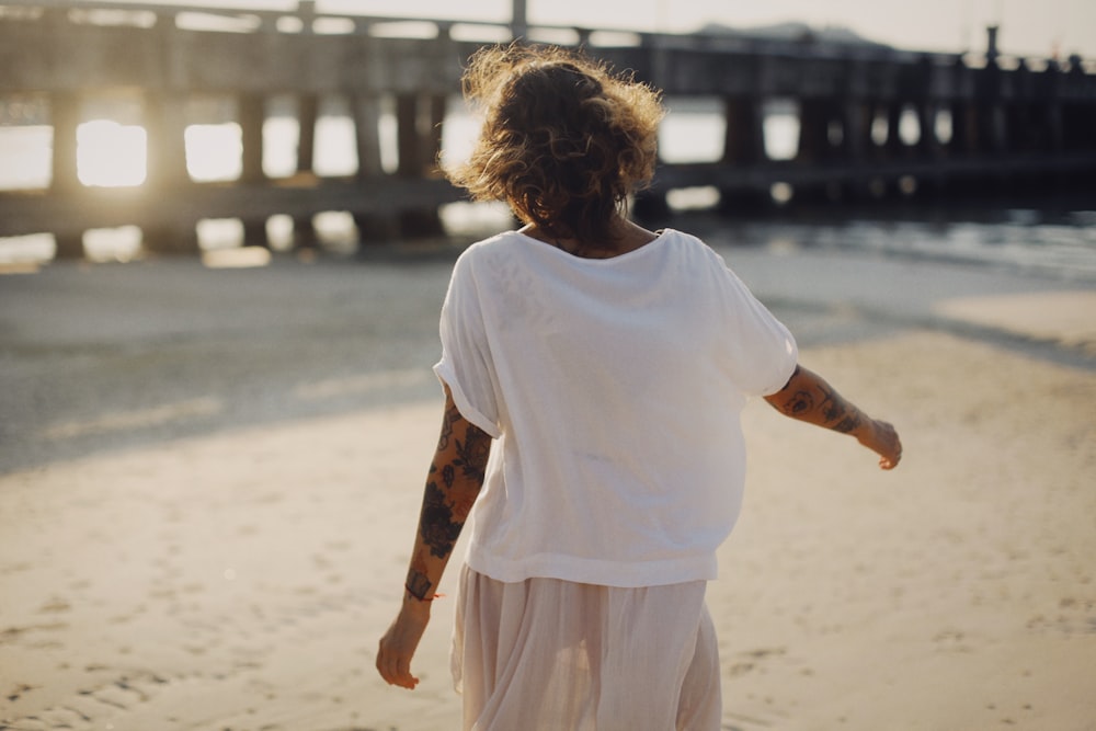 Mädchen in weißem Rundhals-T-Shirt tagsüber am Strand stehend