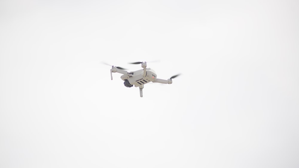 white and black drone flying in the sky